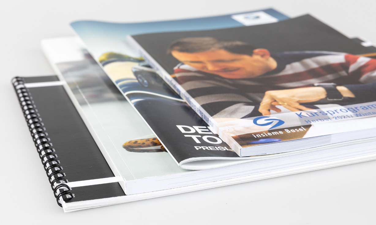 Eine Nahaufnahme von mehreren Broschüren und Printmedien, die übereinander liegen.